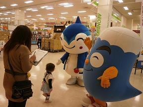 写真:アンケート回答中のお母さんの代わりにゆるキャラのやいちゃんとふじっぴーが幼児の相手をしている様子
